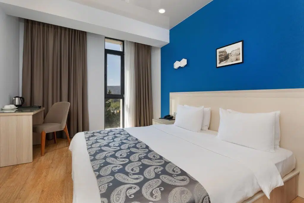 Iveria Inn — Hotel room with a blue accent wall, king bed, and window views.