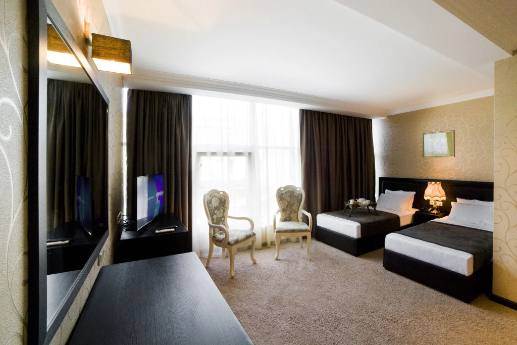 KALASI — Spacious hotel room with two beds, armchairs, large window and mirrored wall.