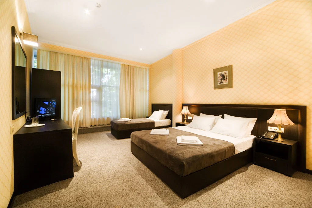 KALASI — Hotel room featuring a double bed, single bed, desk and window with curtains.
