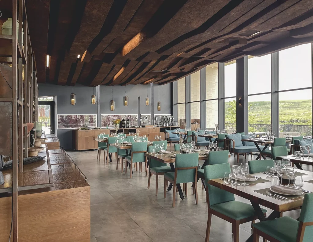 Kass Land Diamond Resort — Modern restaurant dining room with wooden ceiling beams, teal chairs, and large canyon-view windows.