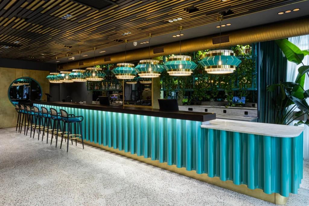 Khedi — Modern bar area with teal wave-patterned counter and pendant lighting fixtures.