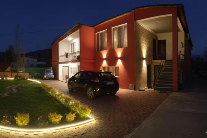 Khvamli 2002 — Night view of the hotel's red and white facade with illuminated landscaping and parked cars.