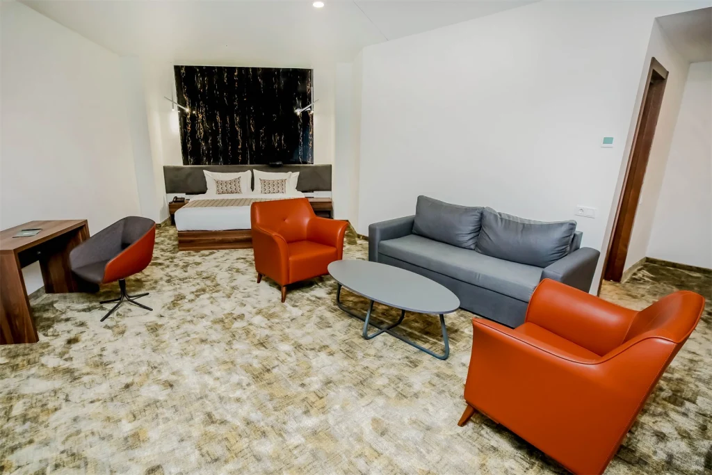 Kutaisi Inn — Suite lounge area with sofa, armchairs, and coffee table near the bed.