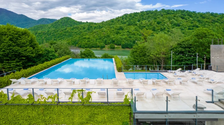 Kvareli Lake Resort — Outdoor infinity pool with sun loungers overlooking the lake and green hills.
