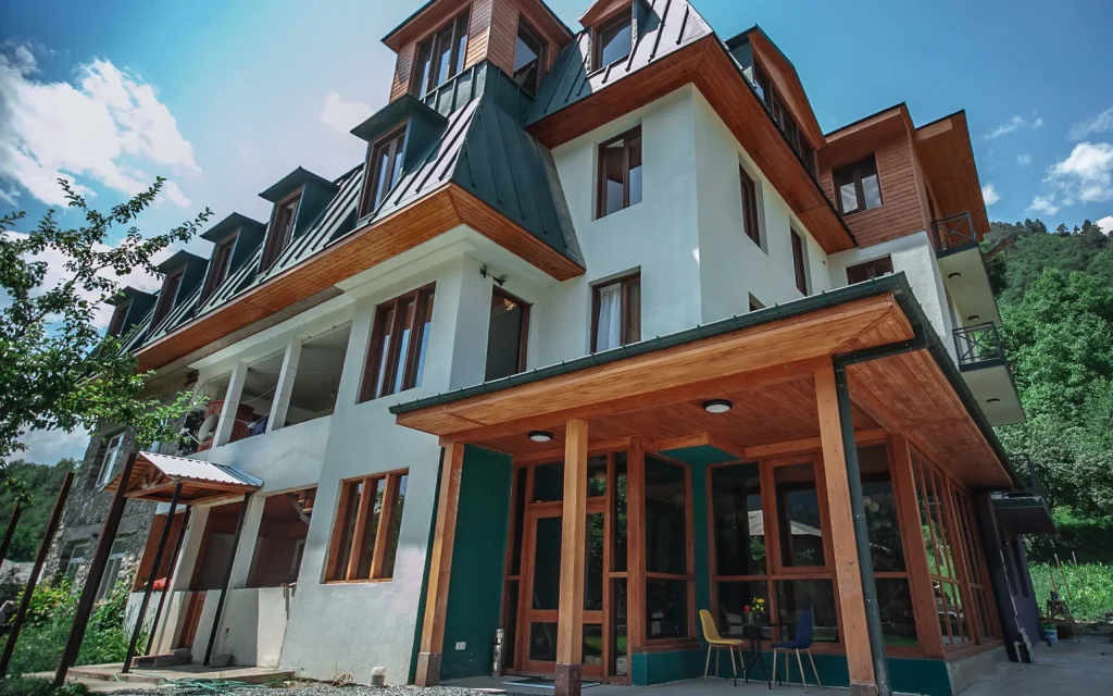 Latour mestia — Multi-story chalet-style hotel building with wooden accents and a covered entrance.