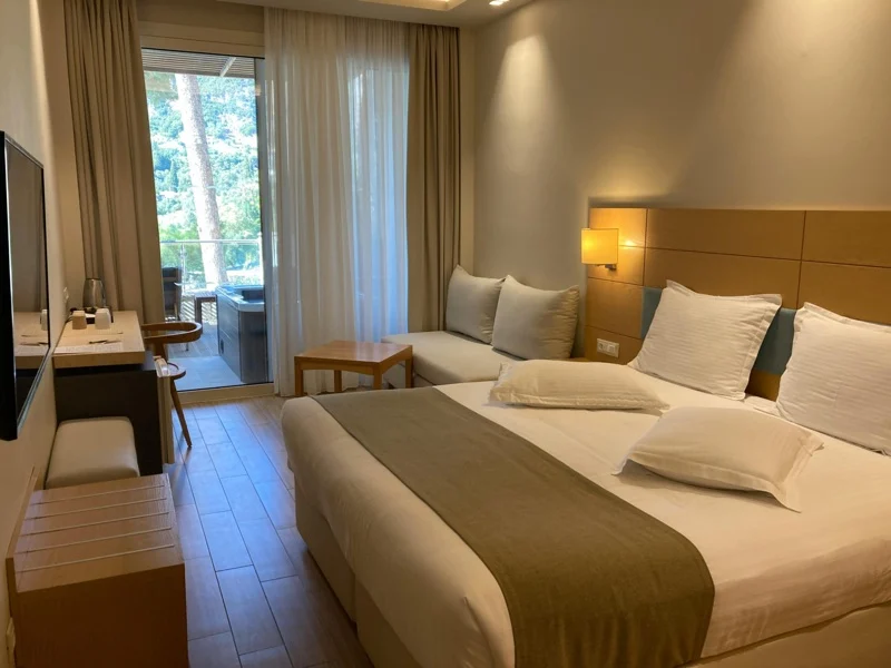 Le Meridien Batumi — Hotel room with a large bed, seating area, and balcony overlooking greenery.