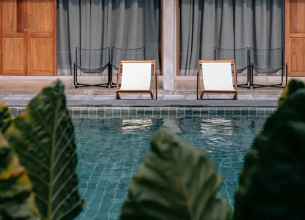 Le Meridien Batumi — Poolside lounge chairs set against wooden doors and curtained cabanas.