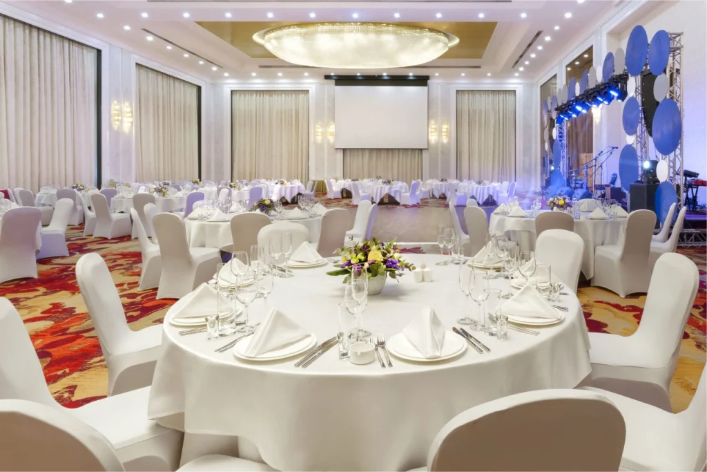 Legends Bar — Elegant ballroom set up with round tables, white linens, and a stage for events.