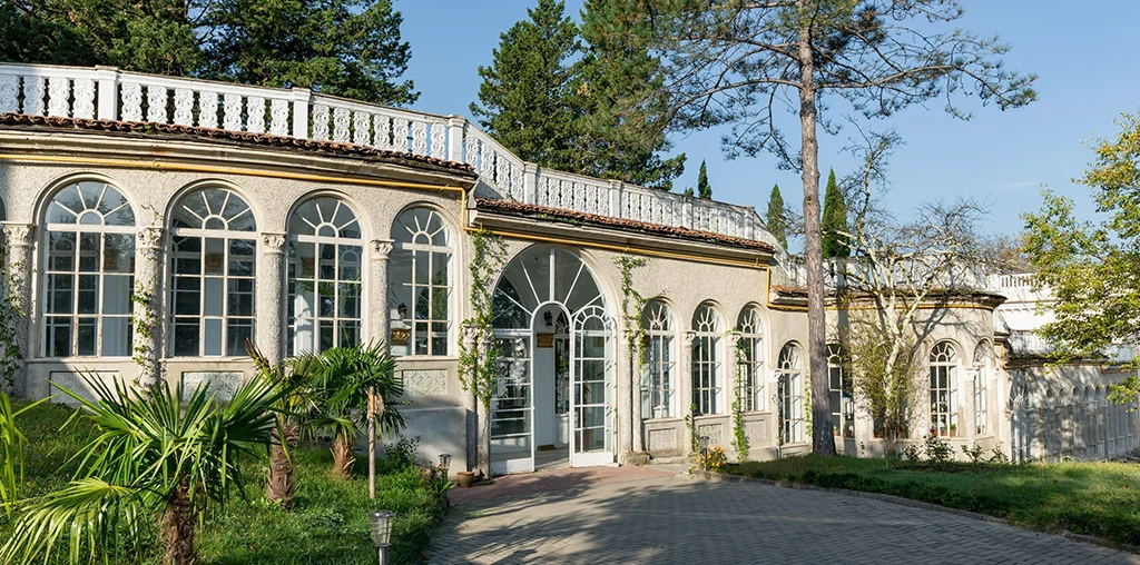 Legends Tskaltubo Spa Resort — Historic building facade with arched windows and a rooftop terrace surrounded by trees.
