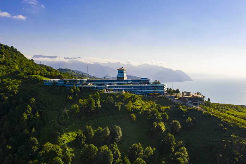 Litz Resort — Aerial daytime view of the clifftop resort building surrounded by green hills and sea.