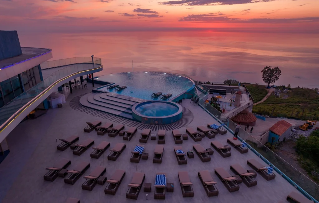 Litz Resort — Infinity pool deck with loungers overlooking the sea at sunset.