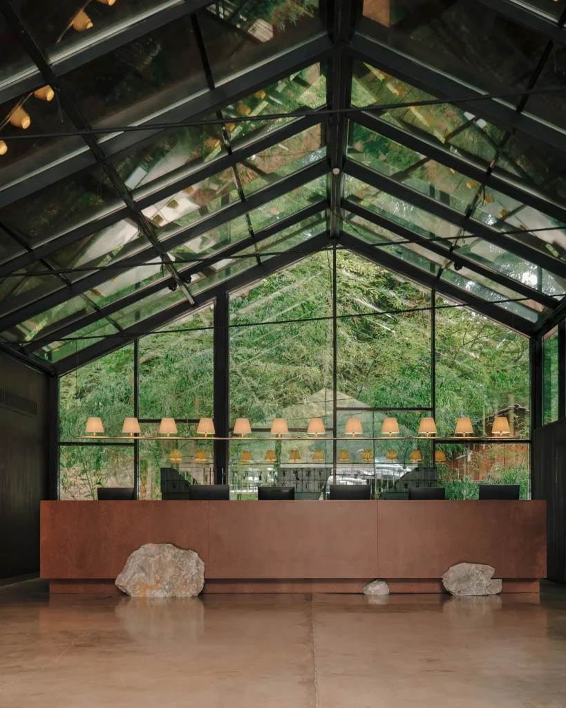 Lopota Lake Resort & Spa — Glass-roofed lobby lounge with reception desk and forest views.