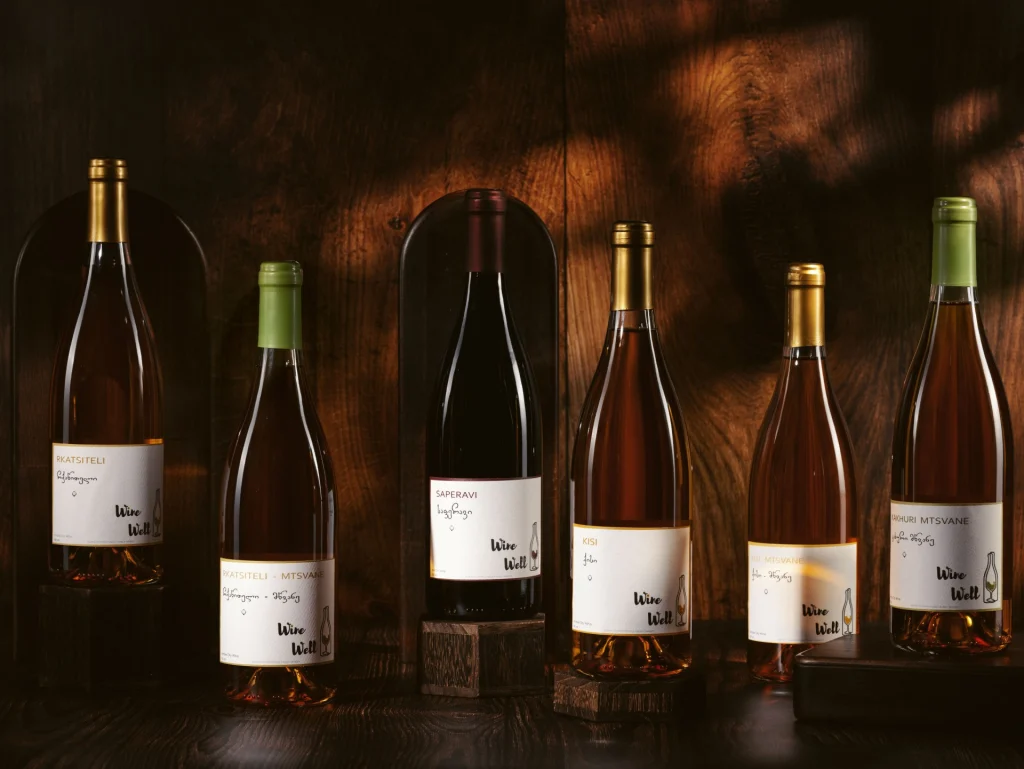 MIDAMO | Wine Village — Assorted wine bottles are arranged against a warm wooden backdrop.