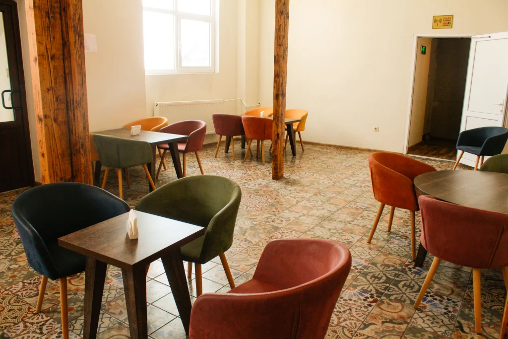 Maharajah Restaurant (Tbilisi) — Dining area with colorful upholstered armchairs, wooden tables, and patterned tile flooring.