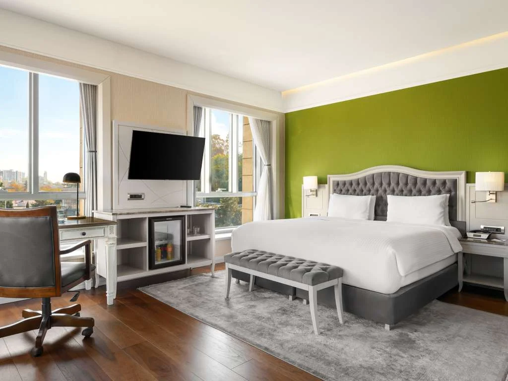 Mercure Tbilisi Old Town — Spacious guest room with green accent wall, king bed, and city-view windows.
