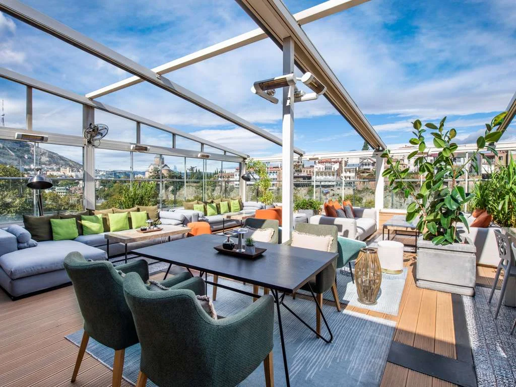 Mercure Tbilisi Old Town — Rooftop terrace lounge offering panoramic views over Tbilisi's old town and hills.