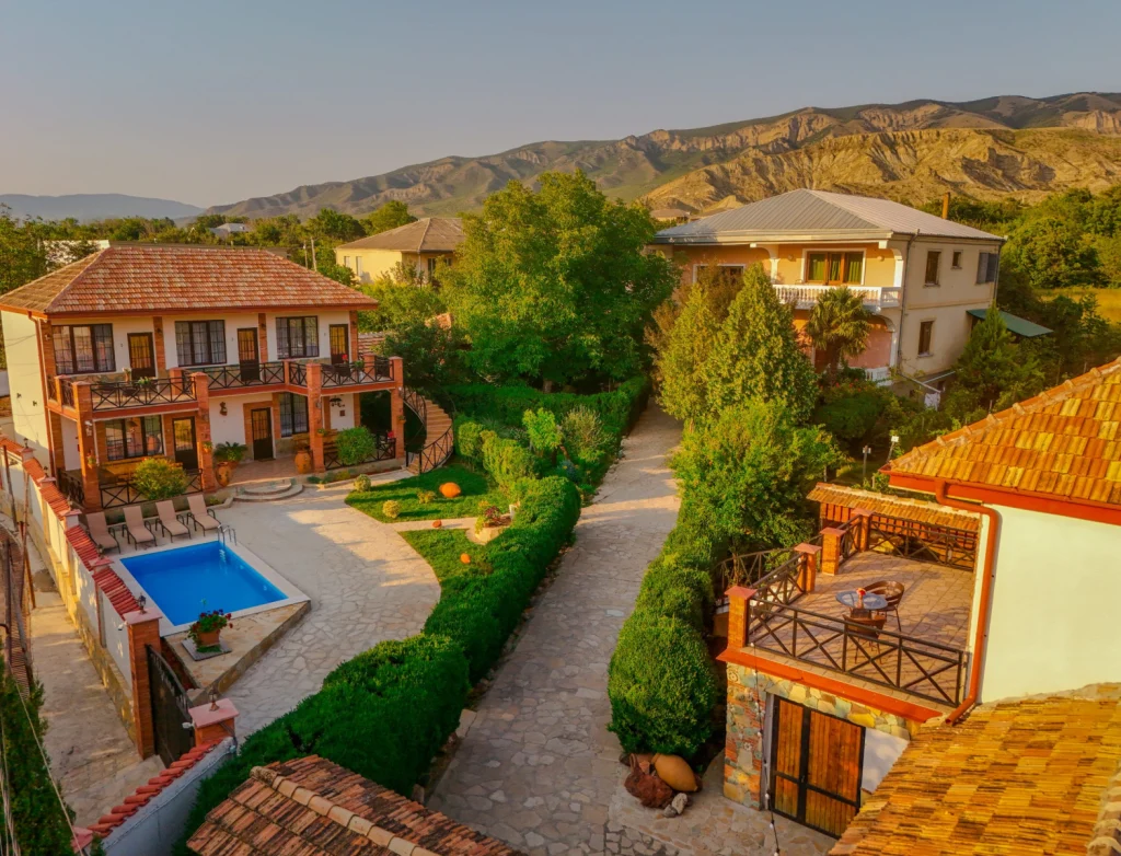 Merebashvili Estate — Aerial view of the estate grounds, pool, and courtyard with mountains in the background.
