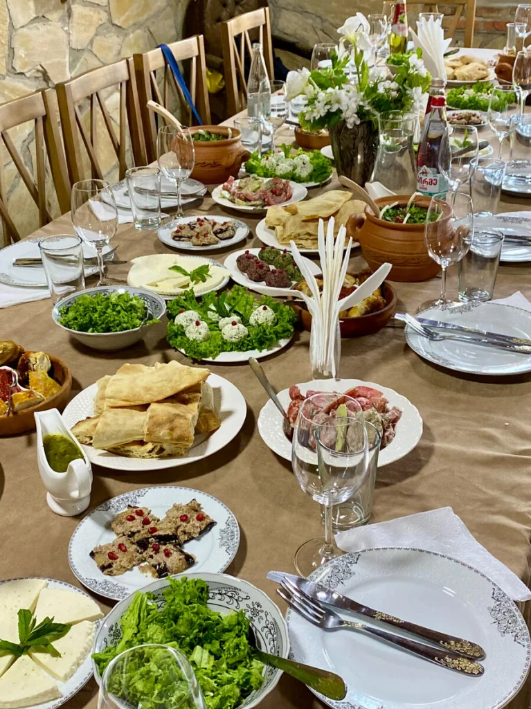 Mirianis Marani — Long dining table set with traditional Georgian dishes and wine glasses.