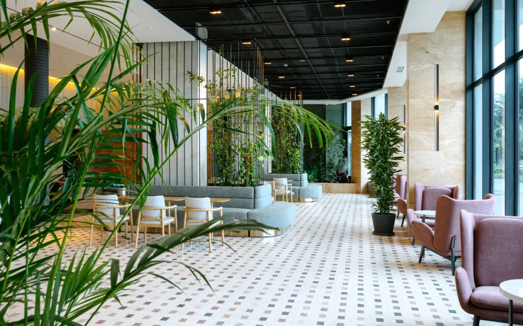Mziuri Gardens — Modern lobby lounge area with plants, armchairs, and patterned tile flooring.