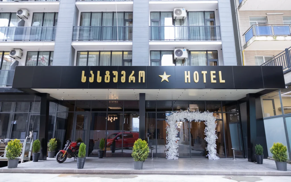 NEW WAVE APART-HOTEL — Hotel entrance facade with illuminated sign, balconies, and landscaped entryway.