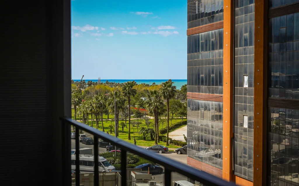 NEW WAVE APART-HOTEL — Balcony view overlooking palm trees, gardens, and the coastline sea.