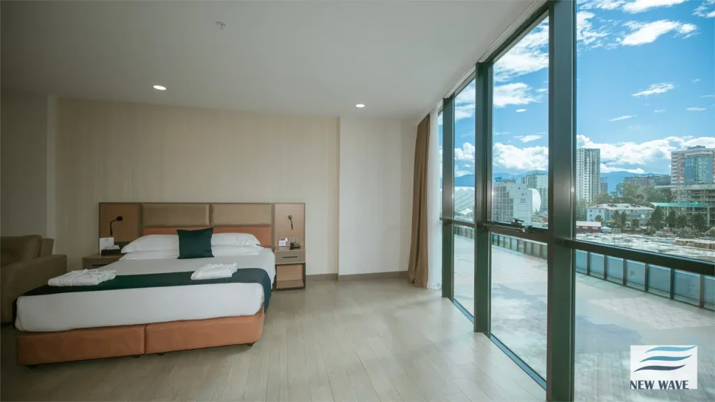 NEW WAVE HOTEL — Spacious bedroom with large windows offering panoramic city and mountain views.