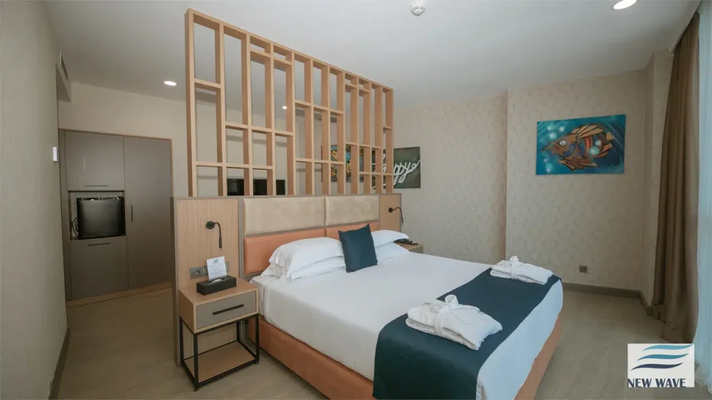 NEW WAVE HOTEL — Modern hotel room with king bed, wooden partition, and artwork on wall.