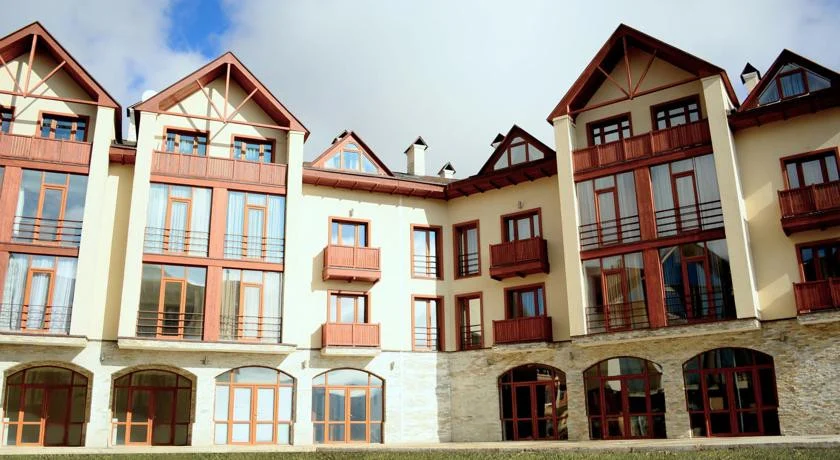 New Gudauri Rooms — Multi-story hotel building facade with balconies and arched ground-floor windows.