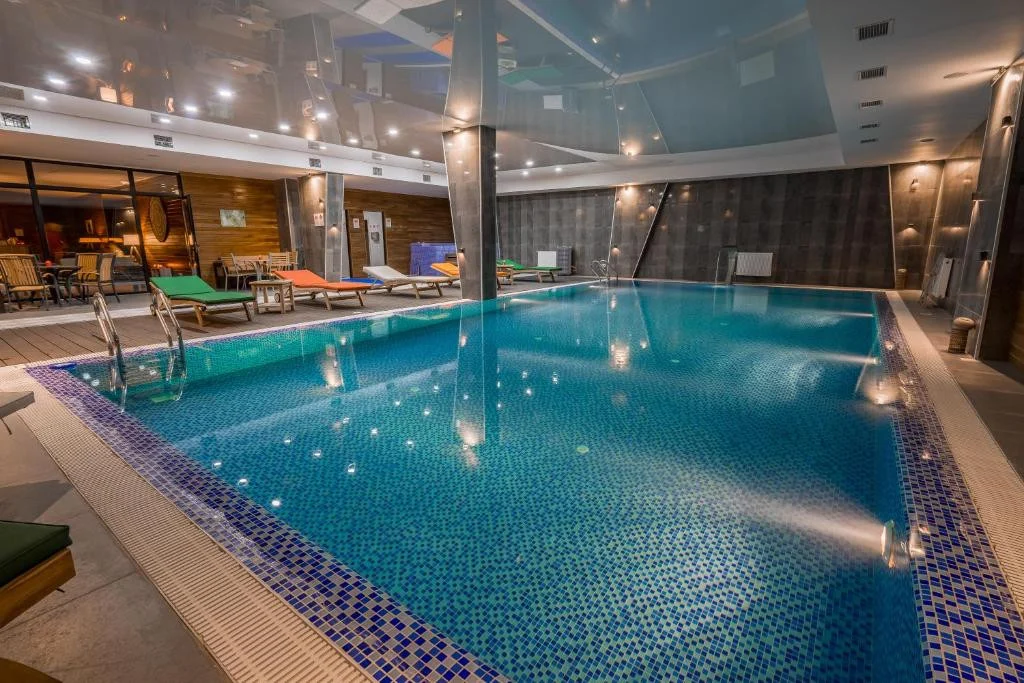 New Gudauri Rooms — Indoor swimming pool with loungers and mosaic tile accents.