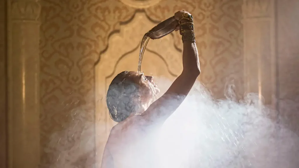 Orbi Beach Tower Hotel — Spa guest pours water over head in a steamy, ornately tiled hammam setting.