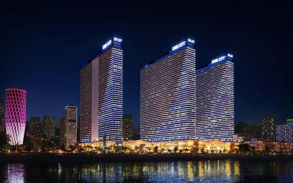 Orbi City Hotel — Orbi City's curved towers illuminated at night along the waterfront promenade.