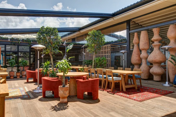Orbi City Hotel — Outdoor lounge terrace with wooden furniture, plants, and decorative ceramic vases.