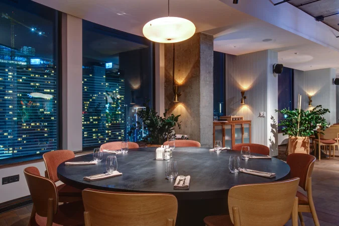 Orbi City Hotel — Elegant restaurant interior with round table seating and city night views through large windows.