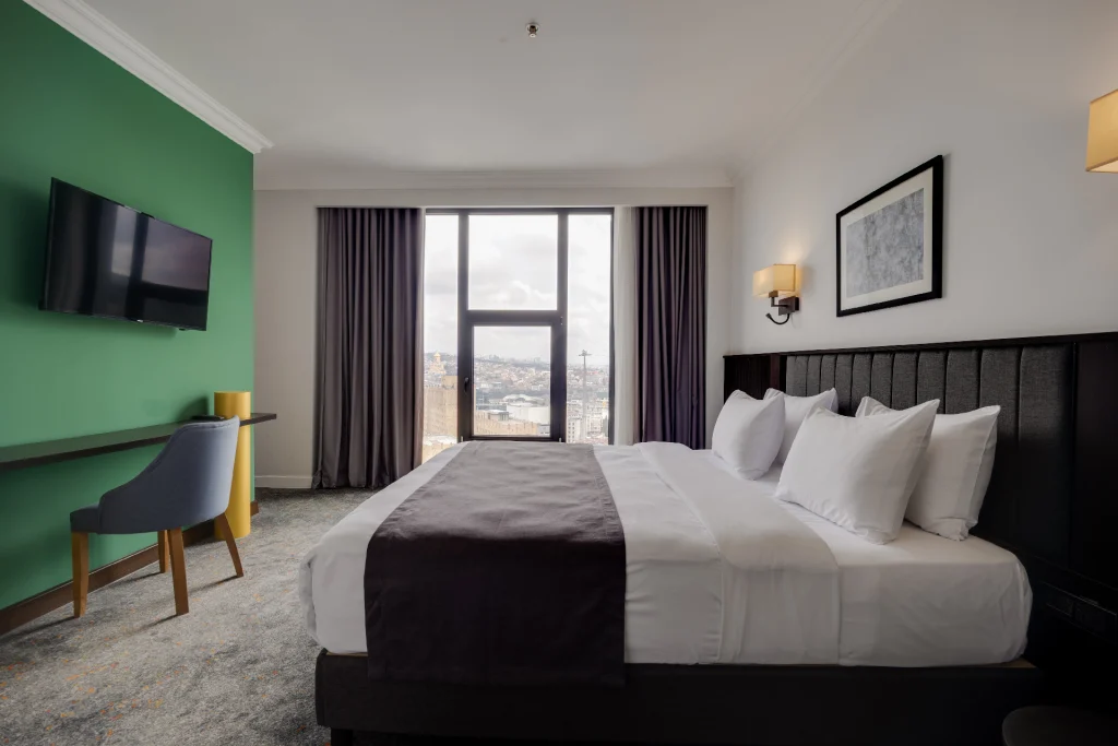 Pine Astoria — Guest room with a large window showing a city view from the hotel.