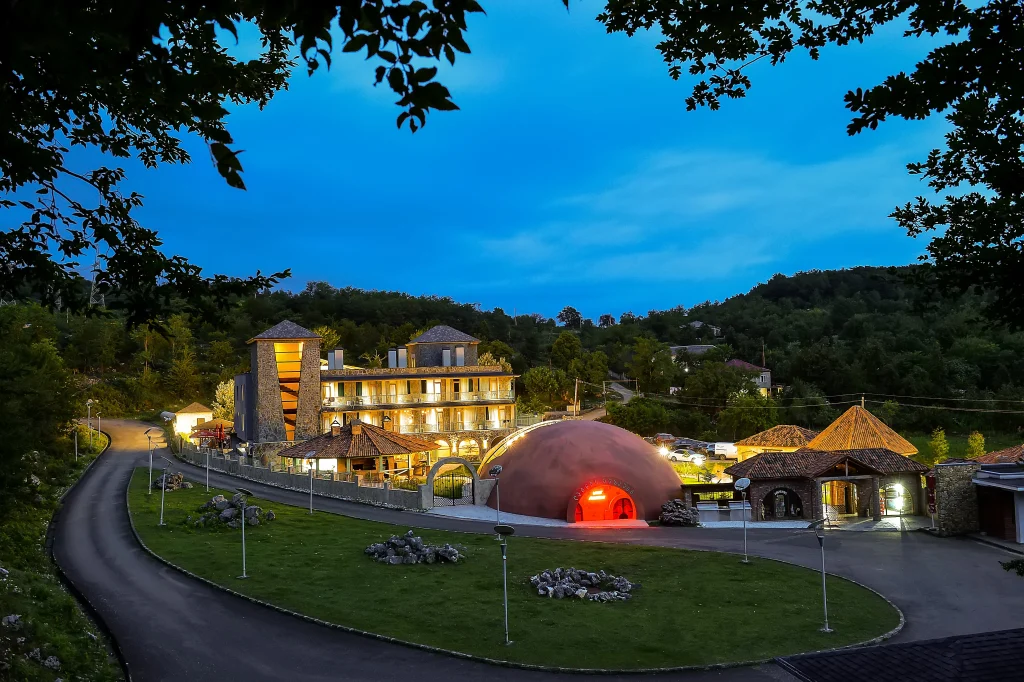 Prometheus Kvevri Wine Museum — Evening view of the hotel complex with illuminated dome-shaped building and stone tower.