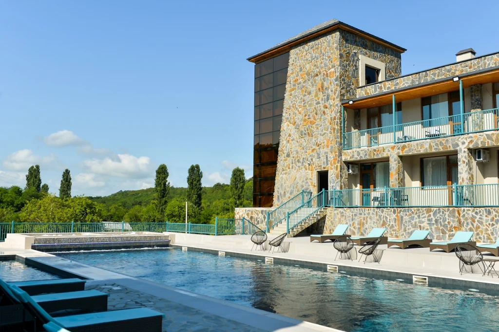 Prometheus Kvevri Wine Museum — Outdoor pool with loungers alongside a stone-clad guest room wing.