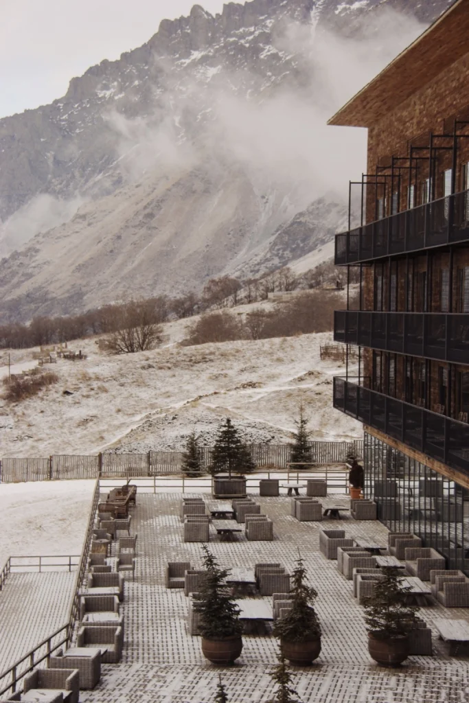 ROOMS Batumi — Hotel exterior terrace with snow-covered seating against a misty mountain backdrop.