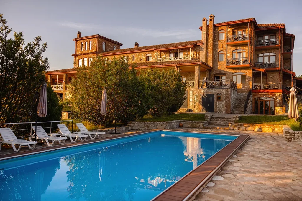 Schuchmann Wines Chateau,  Villas & Spa — Stone chateau building with pool and loungers illuminated at sunset.