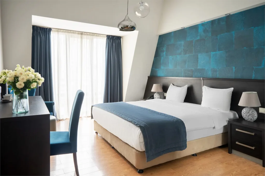 Sephia — Modern guest room with blue accent wall, king bed, and seating area.