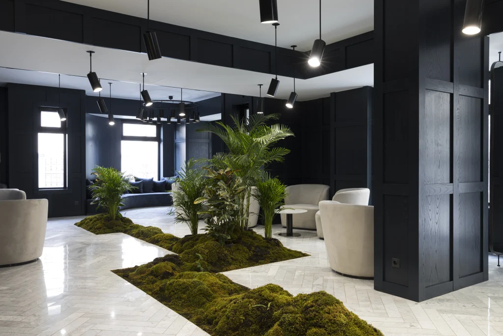 Shota@Rustaveli boutique hotel — Modern lounge area with dark paneling, moss and plant installations, and marble flooring.