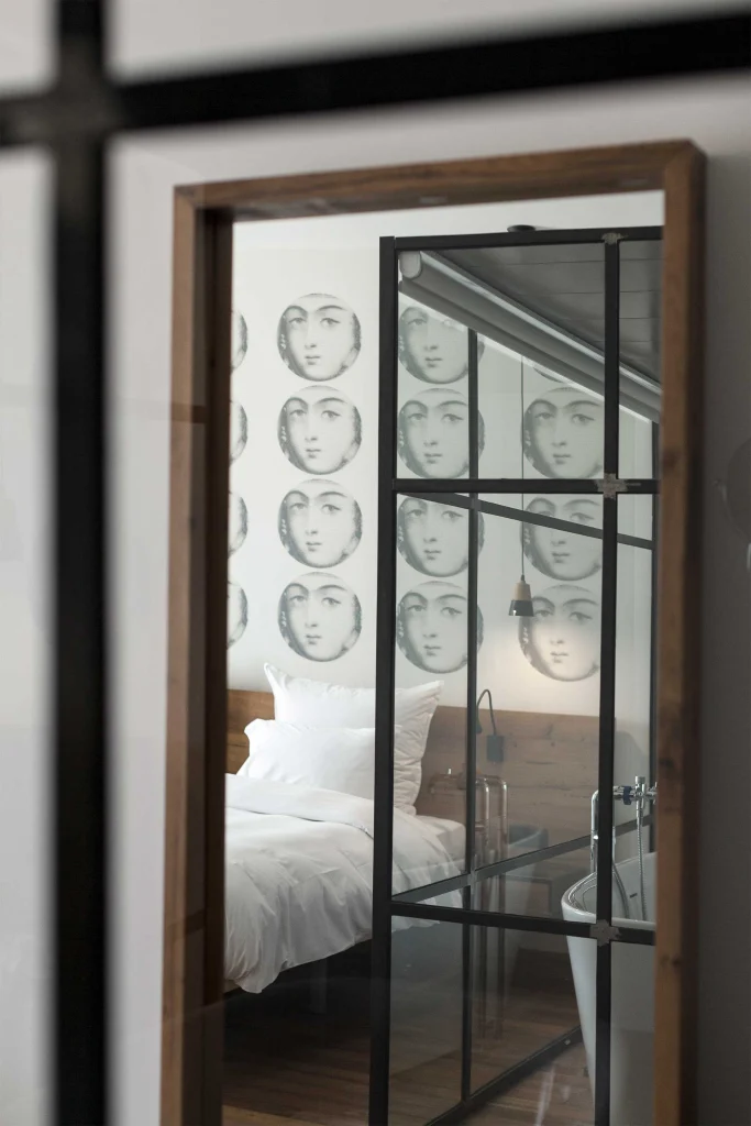 Shota@Rustaveli boutique hotel — Bedroom reflected in a mirror, featuring patterned wallpaper and a freestanding bathtub.