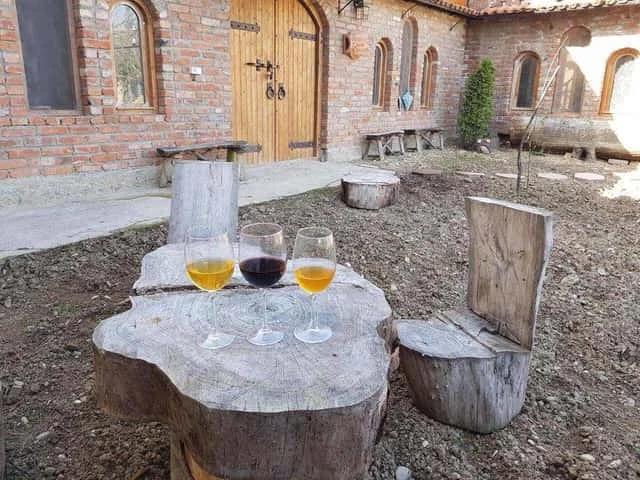 Tevza Winery — Brick winery building exterior with wooden doors and an outdoor wine tasting table.