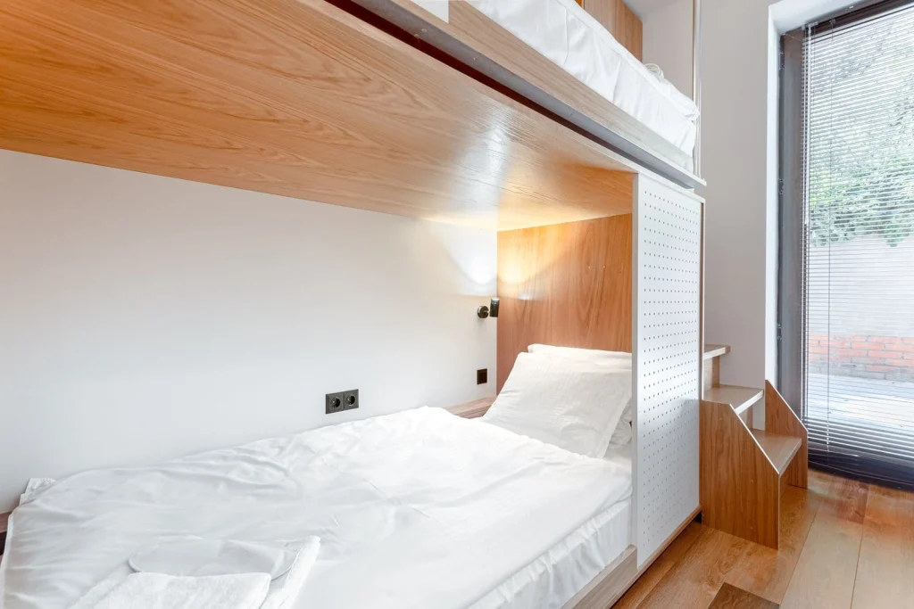 The Tbilisi Pod — Wooden pod-style bunk bed with privacy panel and window overlooking a terrace.