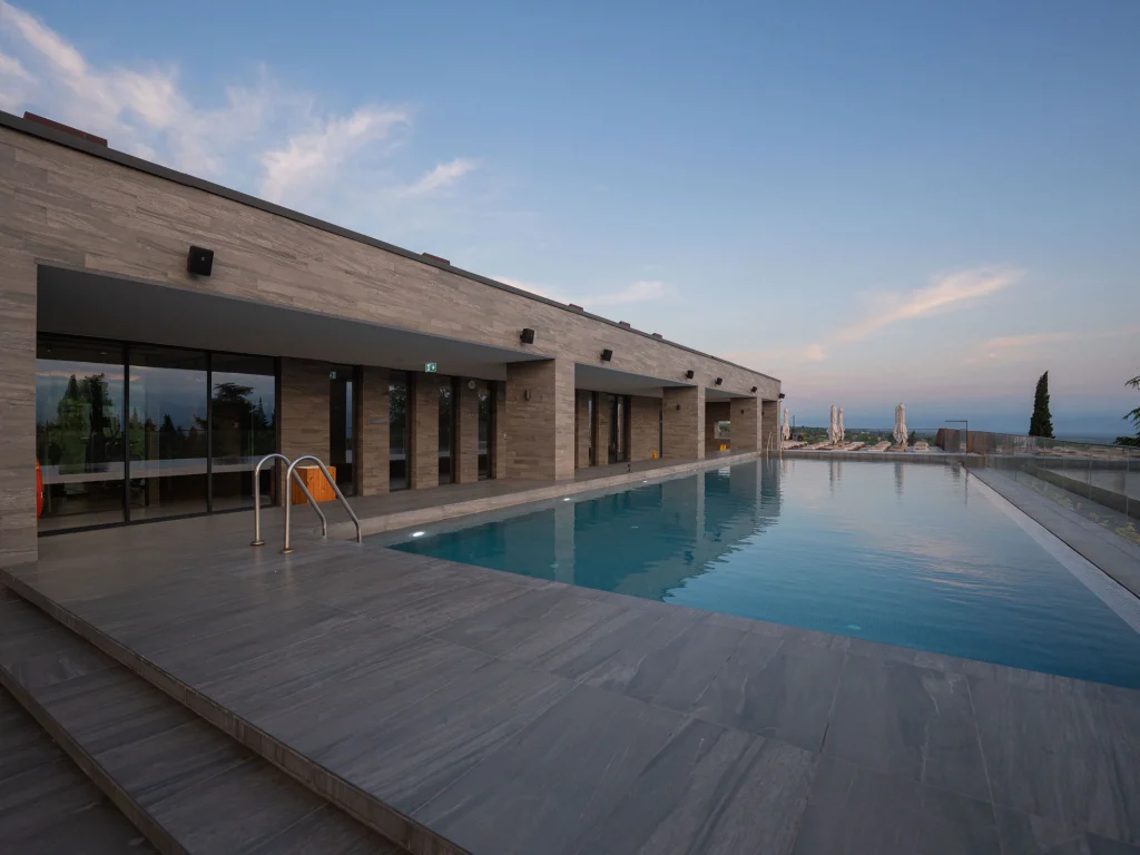 Tsinandali Estate, A Radisson Collection Hotel — Outdoor infinity-style pool deck with loungers overlooking distant hills at dusk.