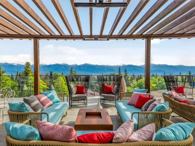Tsinandali Estate, A Radisson Collection Hotel — Terrace lounge with colorful cushioned seating overlooking a panoramic mountain range.