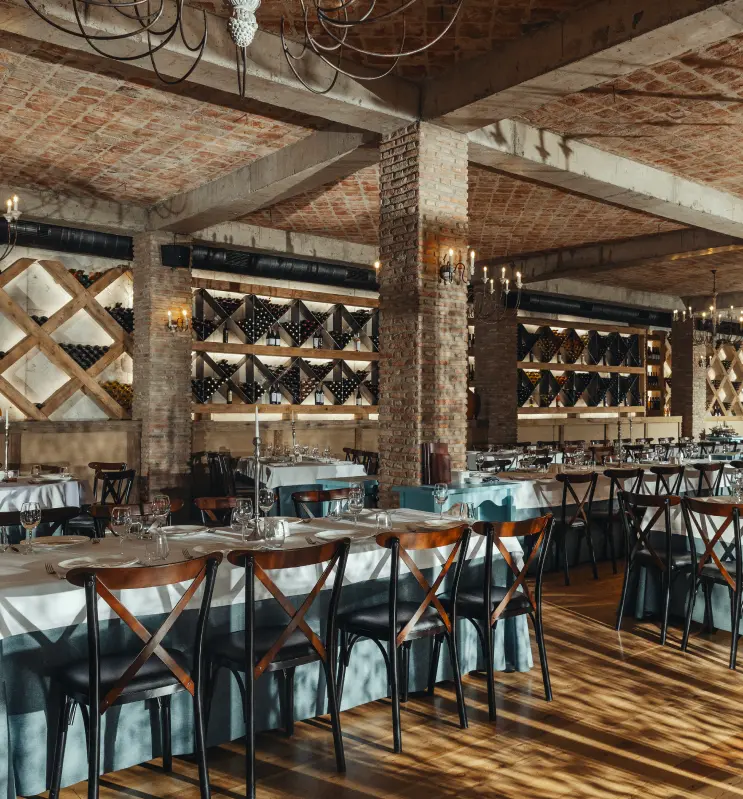 Tsiskvili in Mtskheta — Indoor restaurant with brick walls, wine racks, and long communal dining tables.