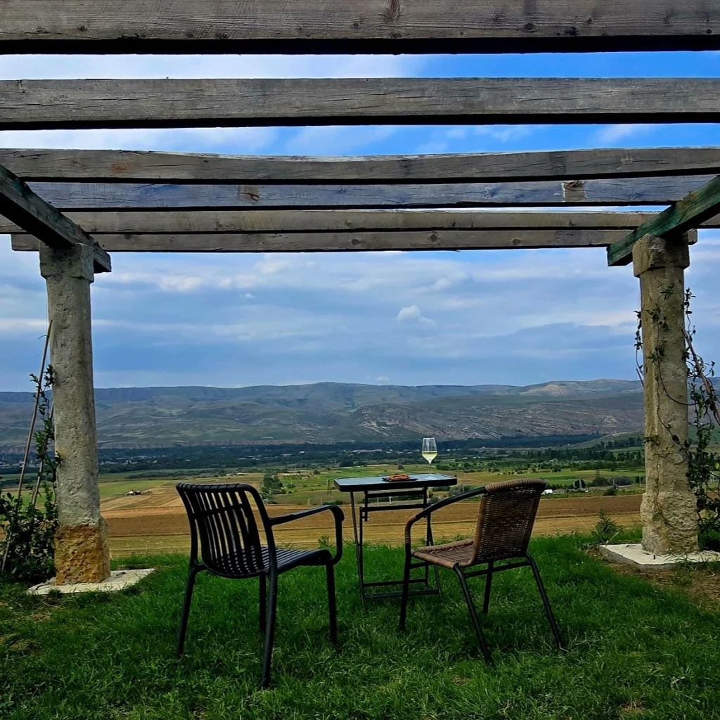 Uplistsikhe Estate — Pergola seating area overlooking a wide valley and distant mountains.