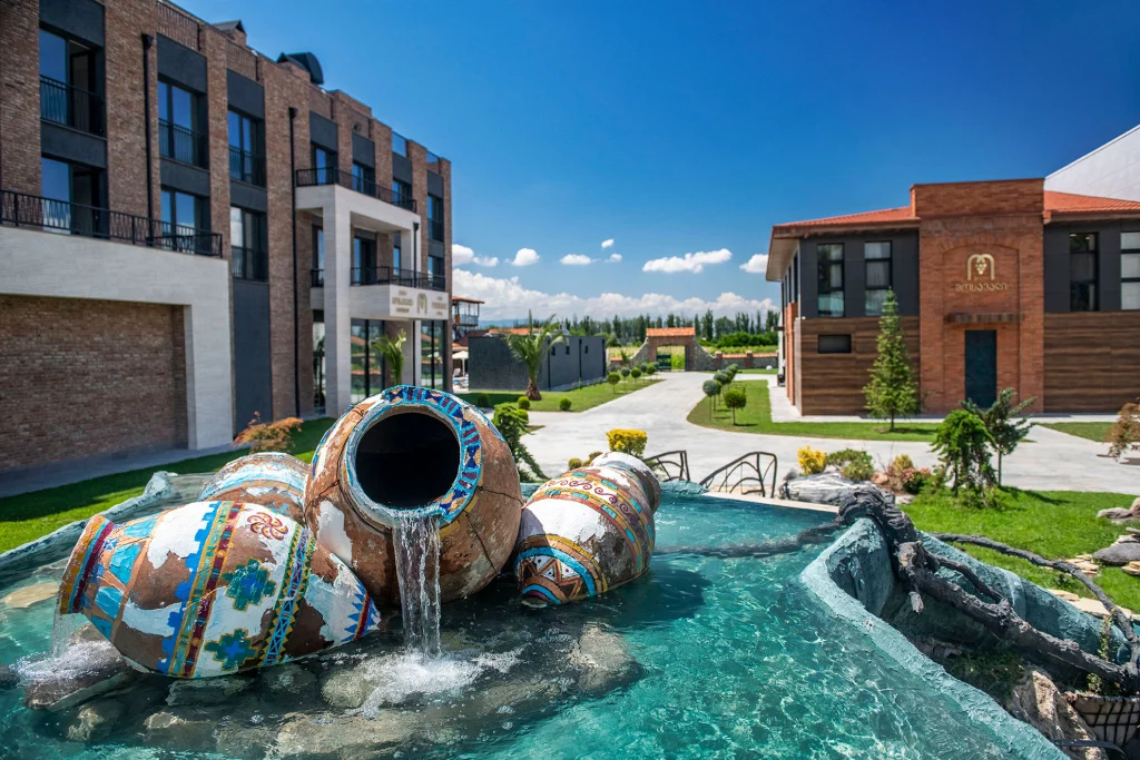 Villa Mosavali — Hotel exterior courtyard with decorative amphora fountain and buildings in the background.