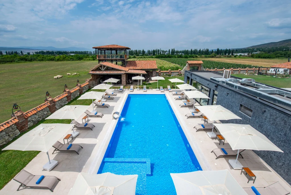 Villa Mosavali — Outdoor swimming pool with sun loungers and umbrellas overlooking vineyards and hills.
