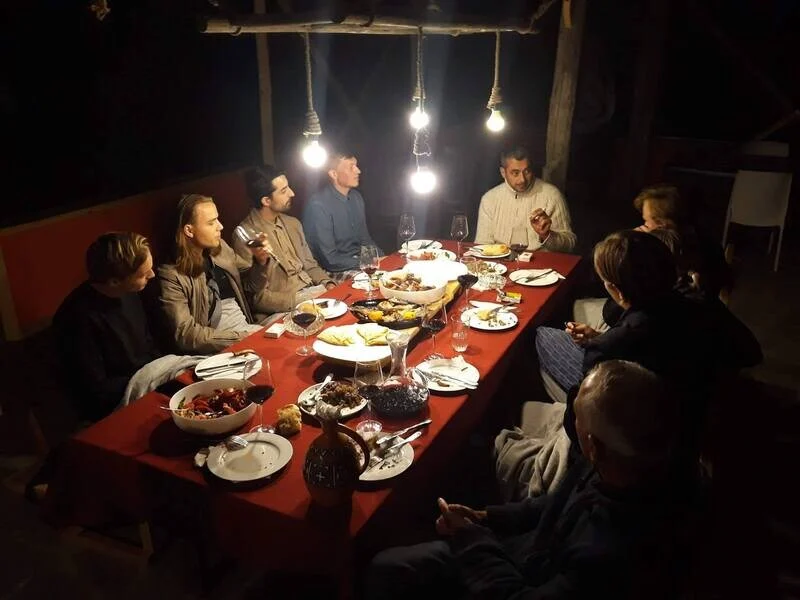 Wine Artisans — Evening dinner gathering with guests seated at a table laden with traditional dishes.
